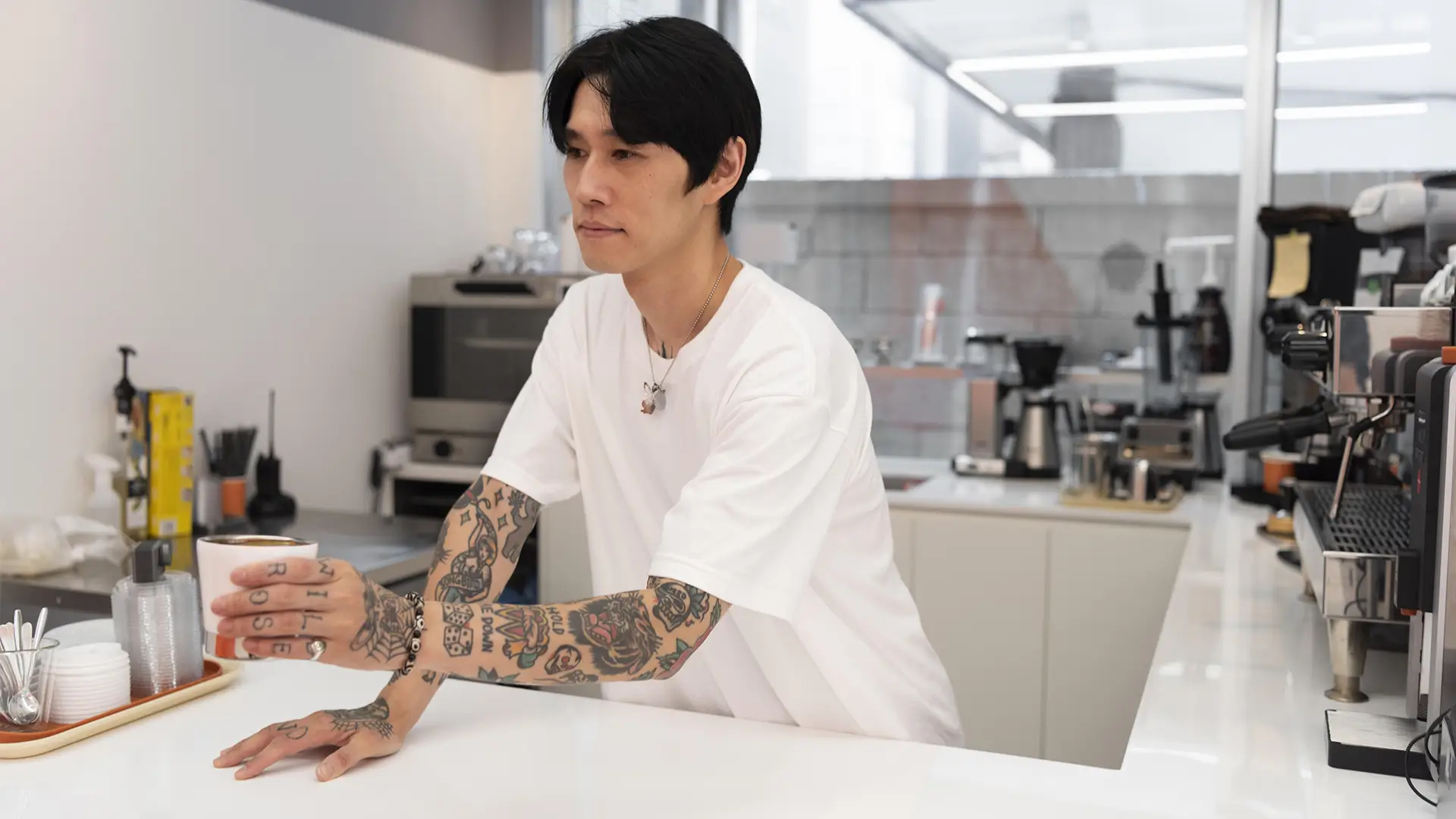 Korean man relaxing in a minimalist coffee shop interior demonstrating the poet core aesthetic.